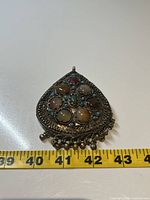 Front side of the vintage Tibetan silver pendant showing nine cabochon stones and detailed filigree work with dangling beads.
