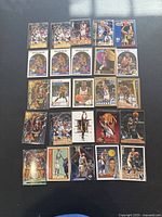 Photo showing the full set of 25 Reggie Miller basketball cards spread out on a black surface, displaying various card designs and images from the 1990s era.