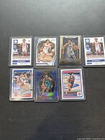 Seven Cade Cunningham basketball cards arranged in protective sleeves and top loaders on a black surface, showing front faces clearly with detailed card designs.