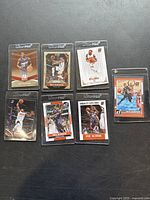 Seven Eric Bledsoe basketball cards laid out on dark surface, each in a protective sleeve highlighting various premium brands and designs