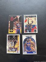 Four basketball cards featuring Mark West laid out on a black surface, showing various action shots and designs.