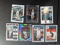 Seven LaMelo Ball basketball cards displayed on a dark surface showing card fronts with various action and posed shots in Charlotte Hornets uniform and different Panini sets.