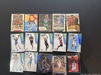 Top view showing 15 basketball trading cards in two rows with players in various action shots, different card designs including holographic ones.