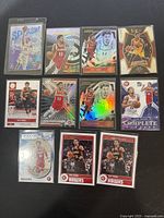 Full view of 12 Trae Young basketball cards laid out on black surface showing various Panini card designs and inserts.