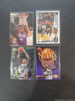 Four Vin Baker basketball trading cards from Milwaukee Bucks in protective sleeves, showing different poses and styles on a black background.