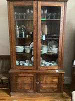 Front view of solid wood hutch displaying glass doors with dishes and glassware inside.