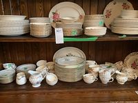 Wide view of wooden shelves filled with multiple stacks of plates and cups in various floral patterns.