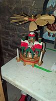 Full view of the Christmas pyramid showing the wooden fan blades on top, hexagonal base, and festive painted details in red, green and white.