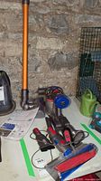Main vacuum body, attachments, charger and wand displayed on table against stone wall