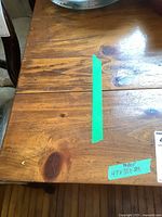 Close-up photo of the wooden table surface showing natural wood grain and knots with green tape indicating dimensions 47x38x29.