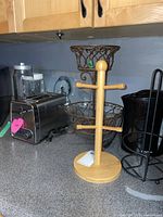 Kitchen countertop with stainless steel Hamilton Beach toaster, wooden mug holder, metal fruit basket, black electric kettle, and paper towel holder.