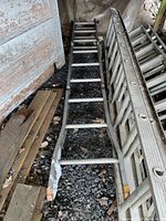 Full length view of aluminum multi ladder showing wear and dirt on one end.