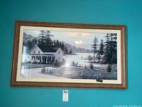 Framed landscape print by W. Saunders showing a lakeside house, vintage car, pine trees, and water with figures. Brown wood frame with white mat.