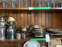 Shelf with several silverplate items including pitchers, baby mugs, chafing dishes, and smaller trays