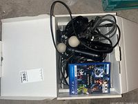 Overhead view of all lot contents in a white box - VR headset cables and Move controllers along with a PS4 game disc case.