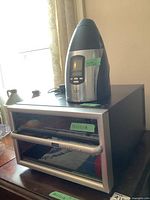 Two wine cooling appliances on a table: a Salton wine fridge with glass door and a Sharper Image wine bottle chiller in stainless steel and black plastic, labeled with green tape.