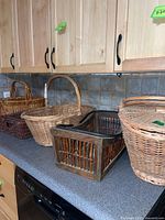 Photo of multiple vintage baskets on a kitchen counter showing different sizes and materials including wooden slats and woven wicker baskets.