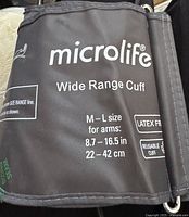 Close-up photo of the black reusable wide range cuff labeled for arm size M-L, 8.7-16.5 inches, latex free, branded Microlife.