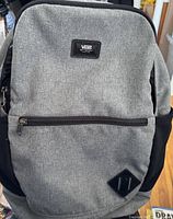 Front view of grey Vans backpack showing zippered front pocket and Vans label
