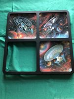 Black display frame with four slots, holding three Star Trek Enterprise plates with the fourth slot empty.