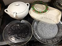 White ceramic soup terrine with lid, large white ceramic platter with raised edge, glass Christmas plate with holly berry motif, two Princess House glass plates including one with Fantasia pattern