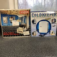 Photo showing boxed Waring Under Cabinet Blender with Can Opener and Cold Keeper Mini Refrigerator with Car Adapter on table.
