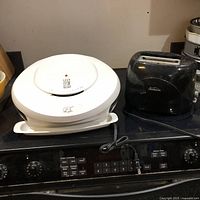 White George Foreman grill and black Oster two-slice toaster on stove top