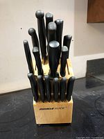 Front view of the wooden block holding multiple black handled knives and utensils with 'Miracle Blade' branding visible.