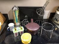 Overview of kitchen items on countertop including spice shakers, roasting stands, popsicle molds, juicer, microwave pot, and straw holder.