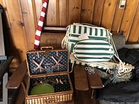 Green and white hanging swing chair, picnic basket with plates and drinkware, and folded US flag on wooden chair
