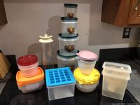 Photo of assorted plastic kitchen storage containers and canisters on countertop.