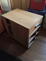 Revolving organizer with wood veneer finish and compartments visible, photographed on wooden floor.