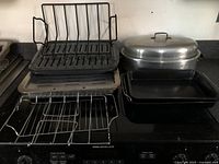 Photo showing multiple roasting pans and roasting racks on kitchen stove