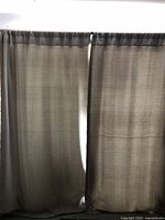 Front view of two light gray thermal drapes with a subtle cream pattern, hanging from a double drapery rod, showing fullness and fabric texture.