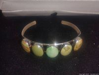 Front angle showing five oval moss agate stones mounted on a 925 sterling silver cuff bracelet with dark velvet background.