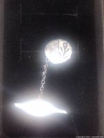 Close-up of the front oval element of sterling silver lapel pin with chain.