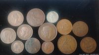 Top view of the lot of coins showing various copper pennies and one smaller silver coin.