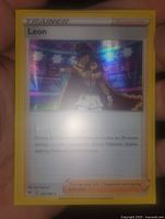 Close-up photo of the Leon holographic foil Pokemon Trainer card showing holographic effect and character illustration.
