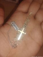 Sterling silver cross pendant necklace with chain and 925 sterling tag held in hand showing details
