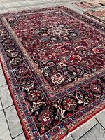 Full view of rug laid on patio showing central medallion, red field and border