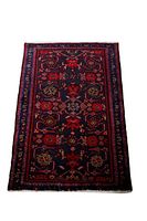 Photo showing the full rectangular handmade Persian carpet with intricate geometric and floral designs in red and navy.