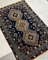 Top-down view of navy handmade rug showing full geometric medallion pattern and floral border