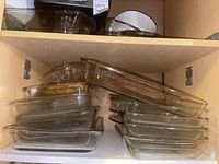 Various glass bakeware on shelf including multiple rectangular and square baking dishes stacked, some marked Pyrex.