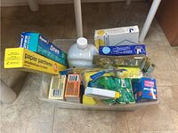 Photo showing full lot laid out on a floor including boxes of parchment paper, a large bottle, wax box, multiple sponges, small boxes, and cleaning cloths.