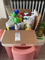 Photo of all assorted cleaning and personal care items packed inside a cardboard box showing multiple spray bottles and containers.