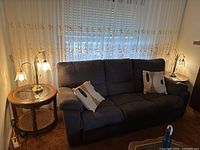 Two metal table lamps on side tables flanking a dark upholstered sofa, showing overall size and placement.