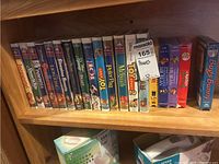 Shelf with multiple VHS tapes of Disney and other cartoons, including Toy Story 2 and Bugs Bunny titles.
