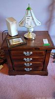 Front view of pine nightstand with four drawers, metal handles, scratches visible on top surface. Several items placed on top (not included).