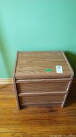 Front view of manufactured wood nightstand showing two drawers and wood grain finish.