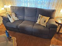 Full frontal view of dark gray three-seat electric reclining sofa with two accent cushions placed on each armrest.